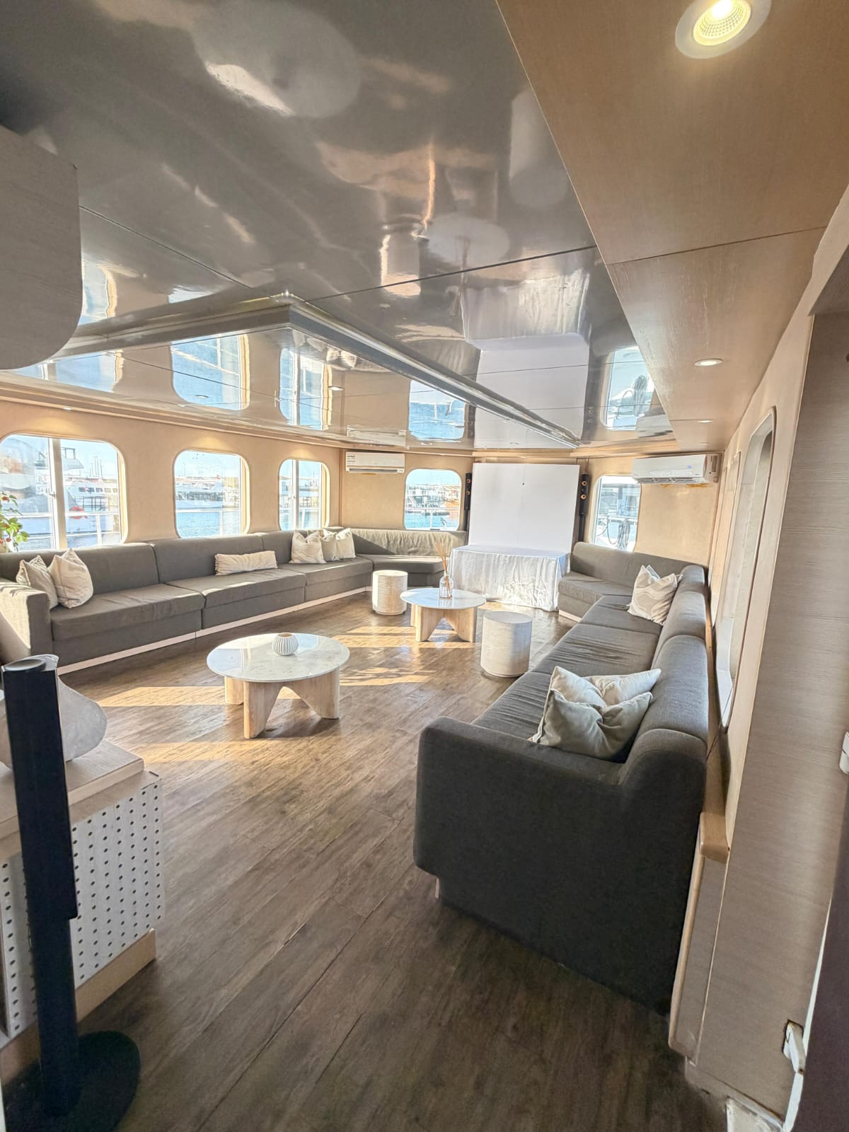 Sunlit lounge with sofas along the windows and round coffee tables