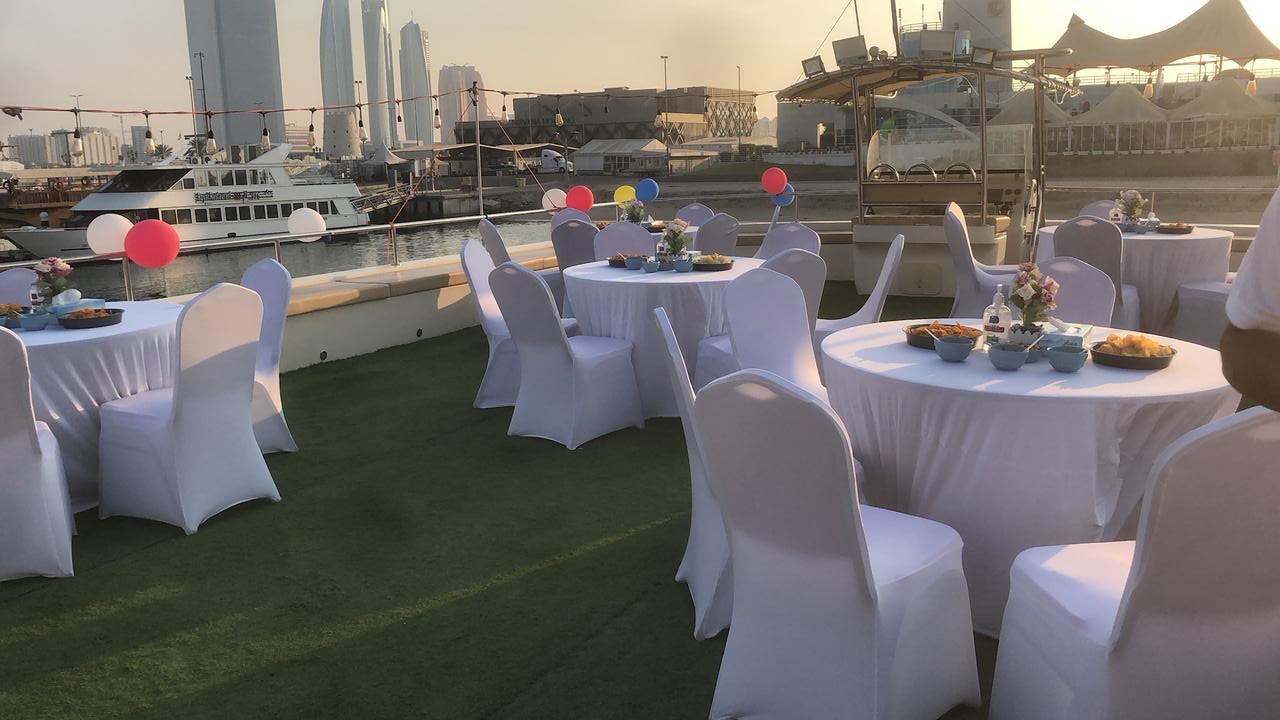Party setup on the upper deck with covered chairs, round tables and balloons at sunset