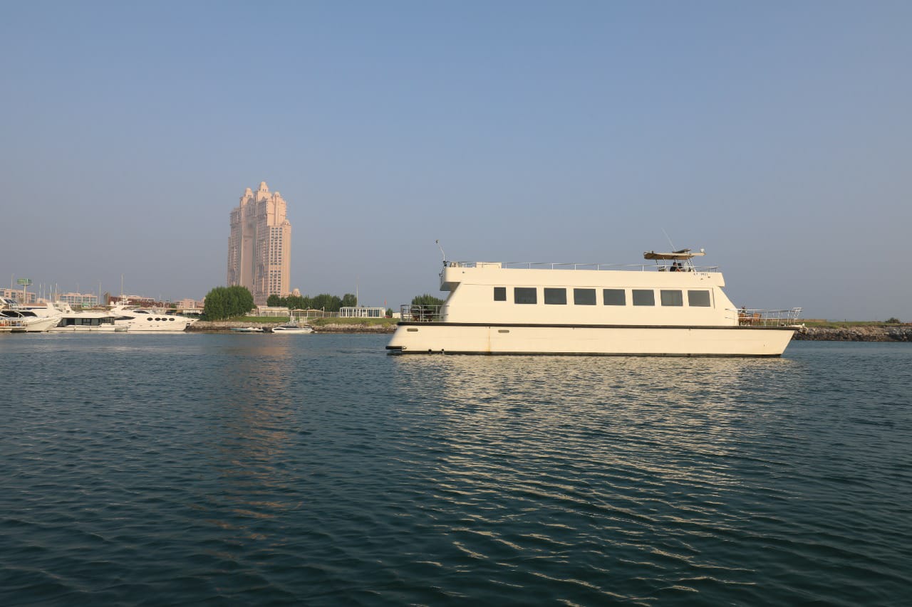 Side view of the yacht cruising past the Abu Dhabi marina and skyline