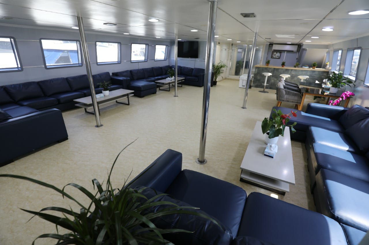 Air-conditioned indoor lounge with navy leather sofas, coffee tables, TV and bar