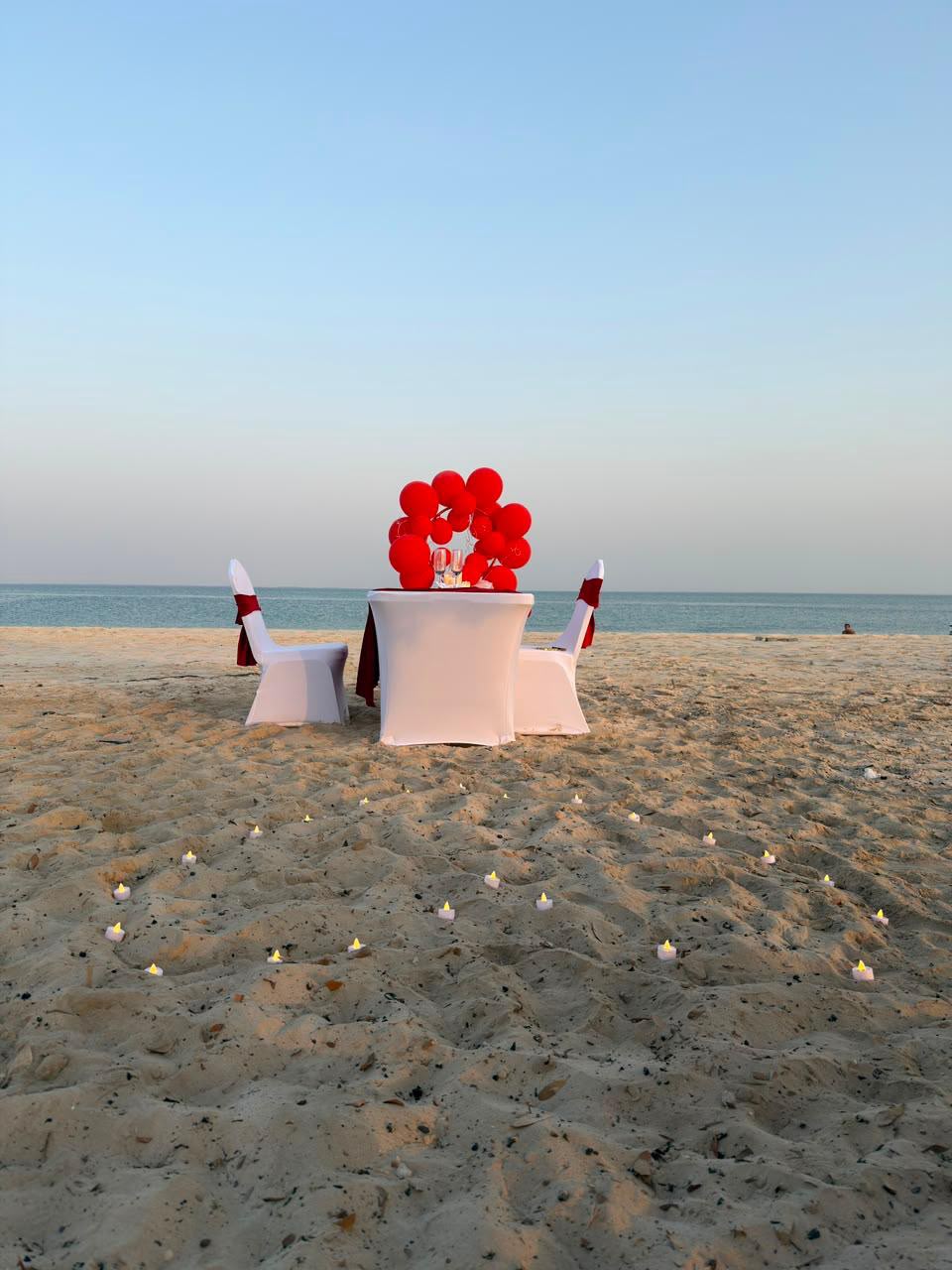 Empty beach table decorated with red balloons and candles for a birthday boat rental in Abu Dhabi