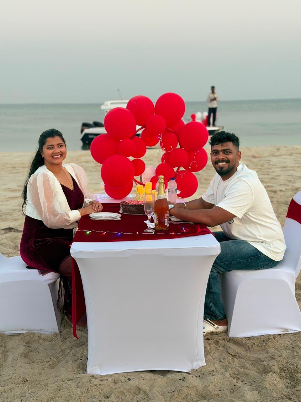 Couple smiling at the birthday table with the charter boat and balloons visible on the water