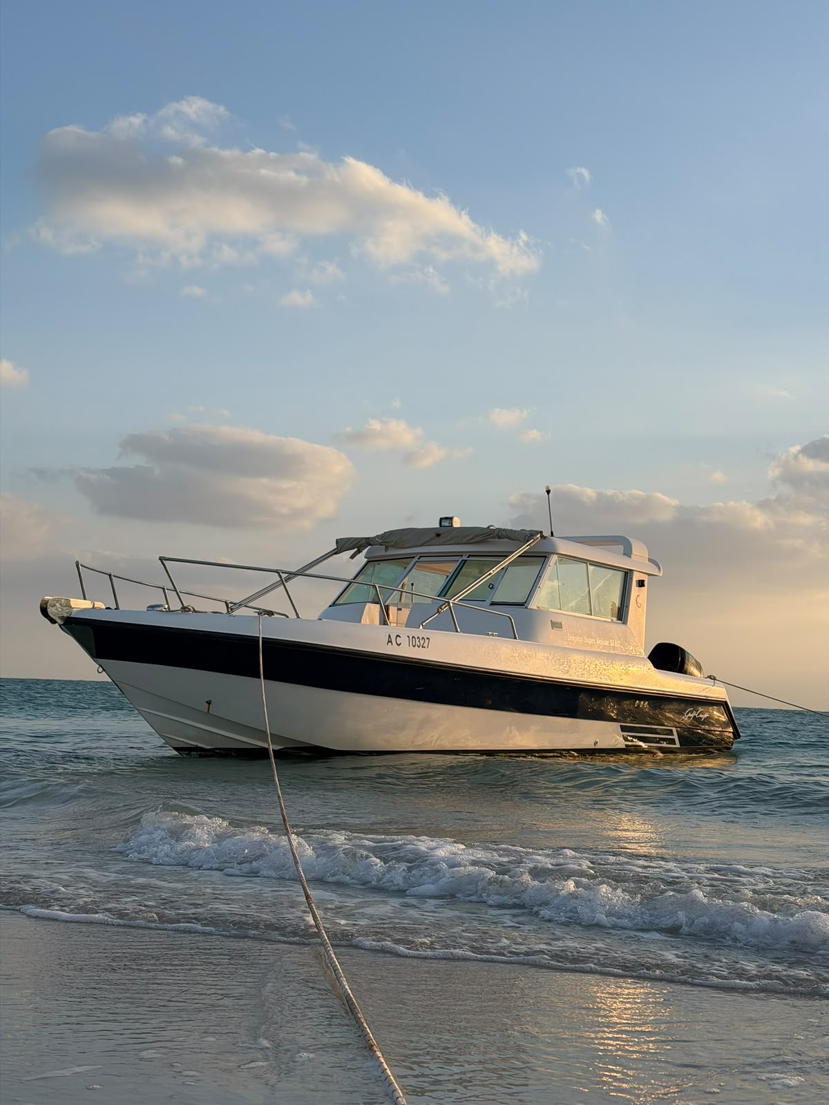 Small waves breaking on the sand in front of the moored boat