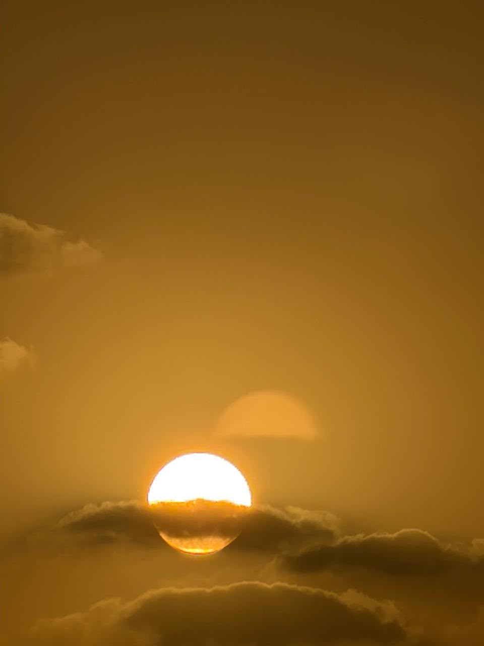 Close-up of the golden sun setting behind clouds over the Abu Dhabi coastline
